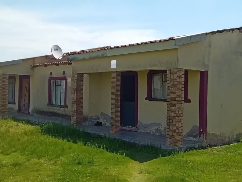 A single-story residential building featuring a covered veranda with brick pillars, showing signs of exterior wear and weathering.