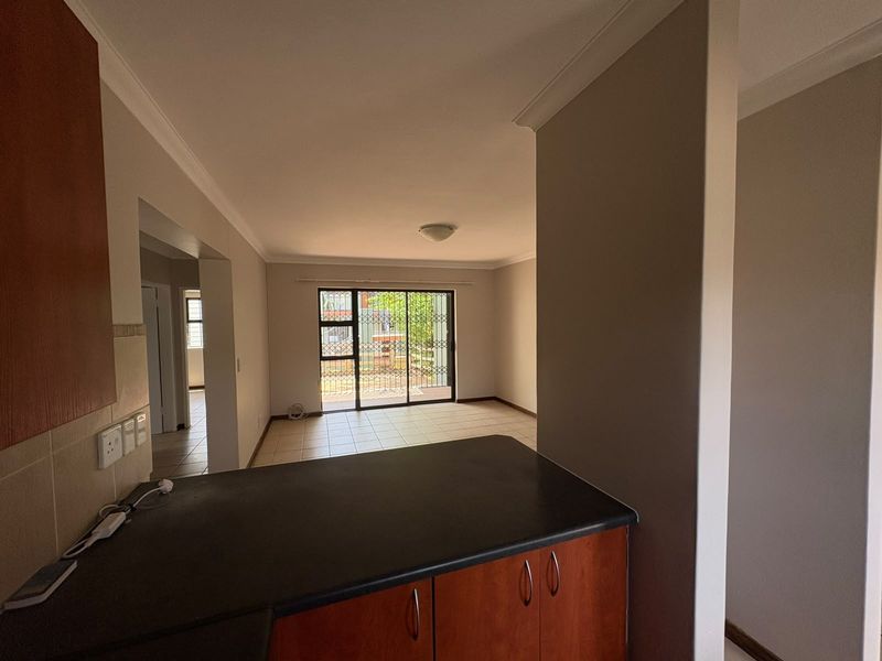 An open-plan living area featuring tiled floors, kitchen cabinetry with dark countertops, and a sliding glass door leading to the exterior.