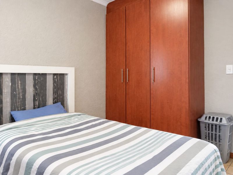 A bedroom featuring a built-in wooden wardrobe and neutral wall finishes, providing functional storage space.