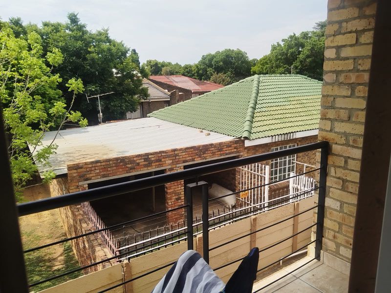 A balcony with metal railings and tiled flooring, offering an elevated view of the surrounding residential neighborhood and neighboring properties.