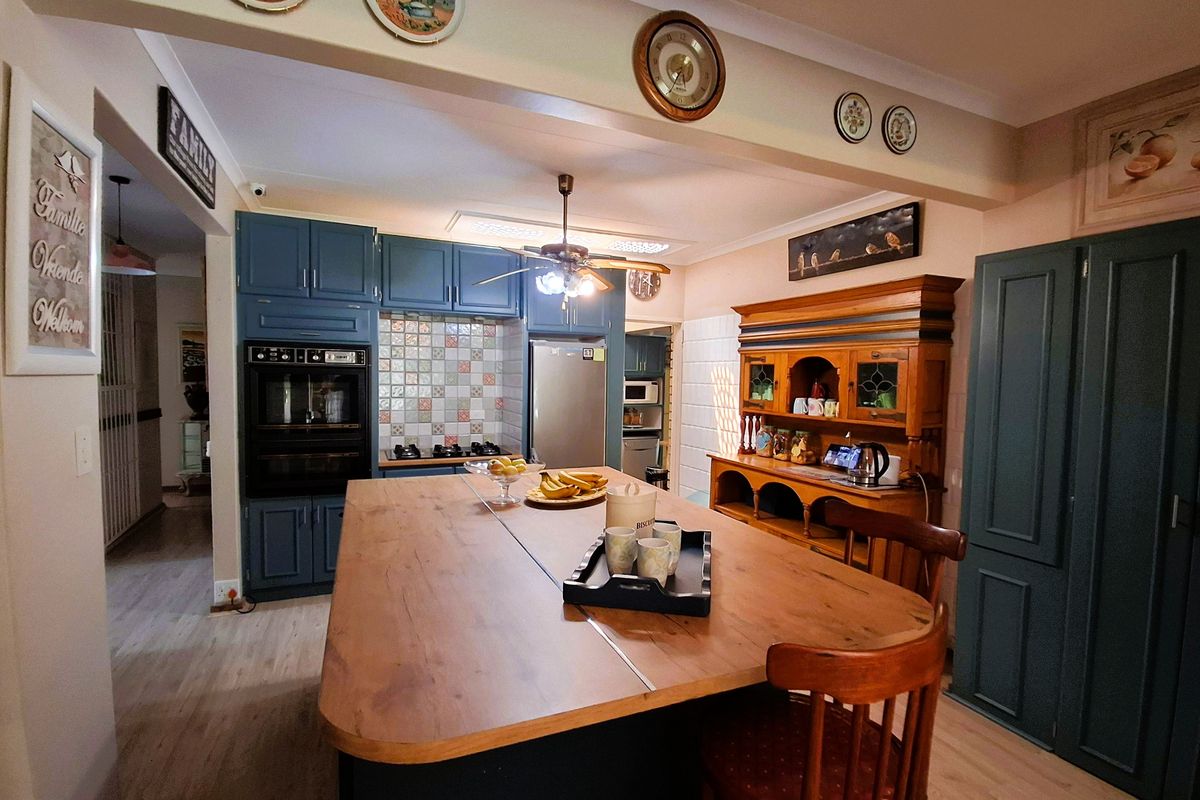 Spacious kitchen featuring blue built-in cabinetry, a central island, built-in oven, and a tiled backsplash, offering a functional layout with ample storage.