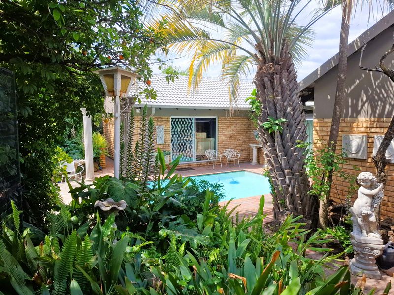 A lush, landscaped garden area featuring a swimming pool, brick paving, and face brick exterior walls, creating a private outdoor retreat.