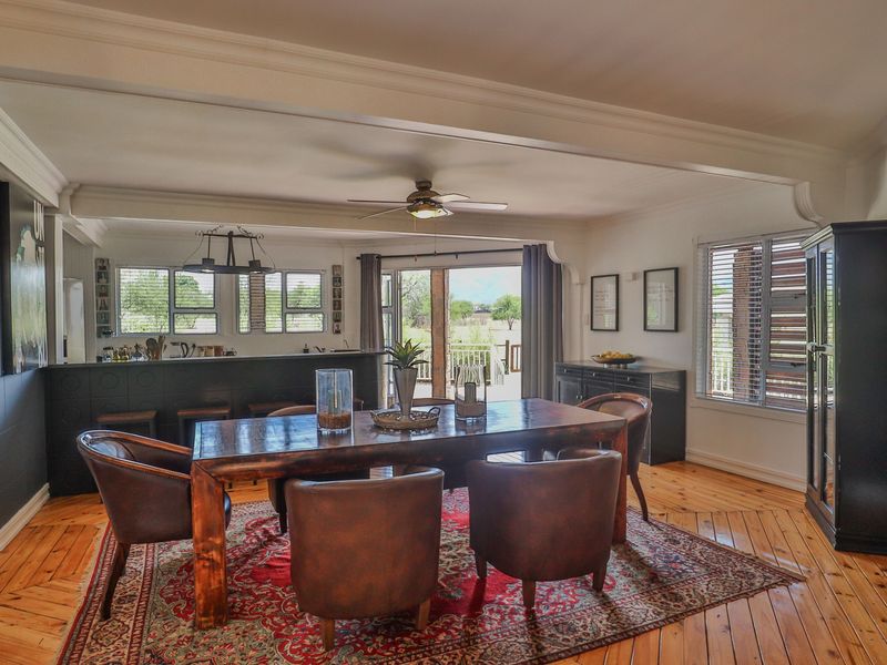 Spacious open-plan dining and kitchen area featuring polished hardwood floors, crown molding, and direct access to an outdoor patio through sliding glass doors.