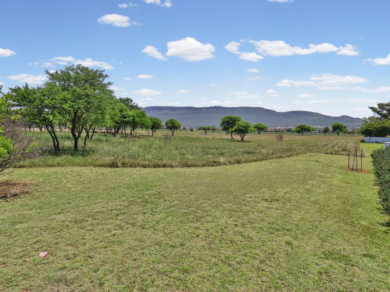Expansive open garden area featuring mature trees and scenic mountain views in the distance.