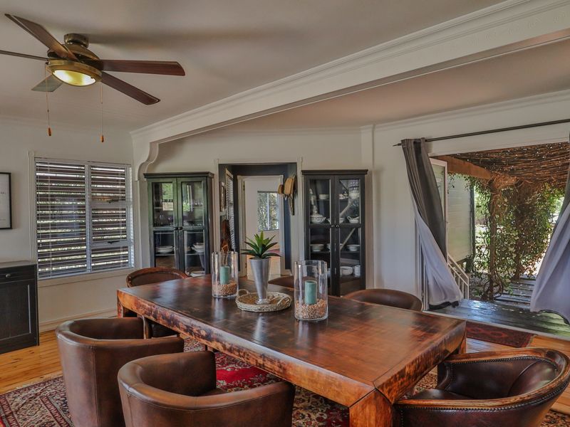 A well-maintained dining room featuring timber flooring, crown molding, a ceiling fan, and direct access to an outdoor patio area.