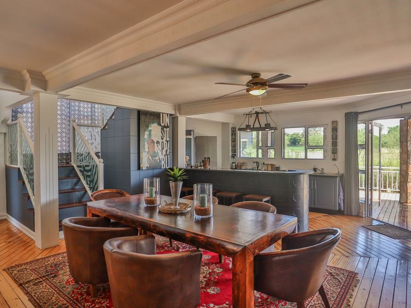 Spacious open-plan living and dining area featuring hardwood flooring, a central kitchen island, and direct access to an outdoor deck through french doors.