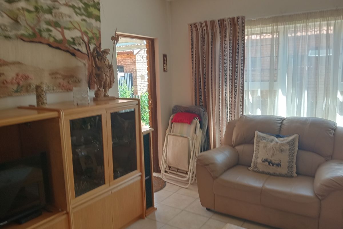 A comfortable living room area featuring tiled flooring and direct access to the exterior, providing a functional space for relaxation.