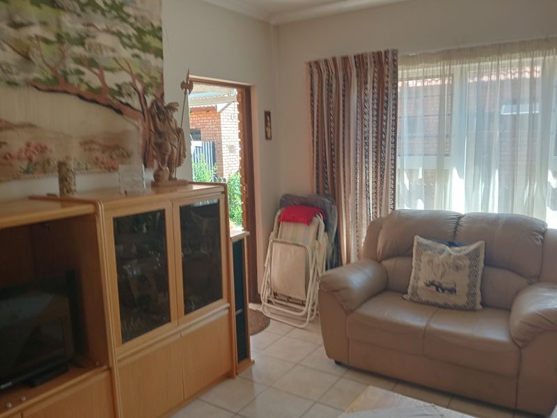 A comfortable living room area featuring tiled flooring and direct access to the exterior, providing a functional space for relaxation.