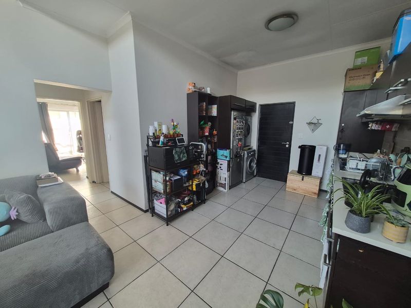 Open plan living and kitchen area featuring tiled flooring and dark cabinetry, offering a functional layout with direct access to adjacent rooms.