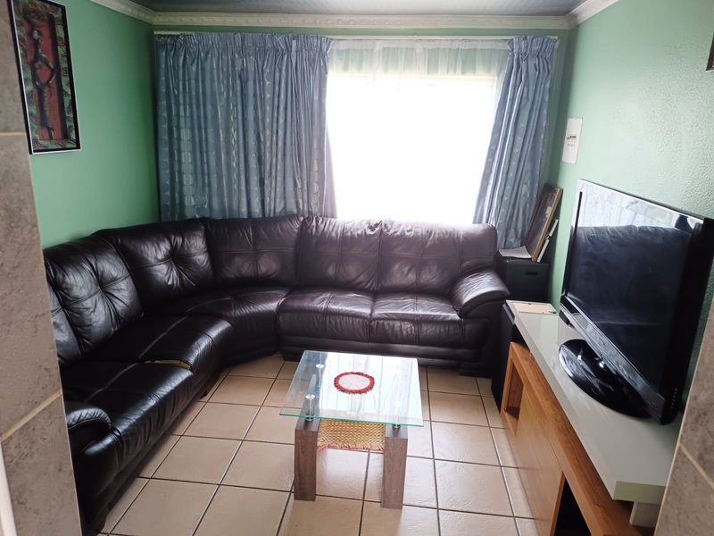 A compact living room featuring tiled flooring and crown molding, providing a functional space for relaxation.