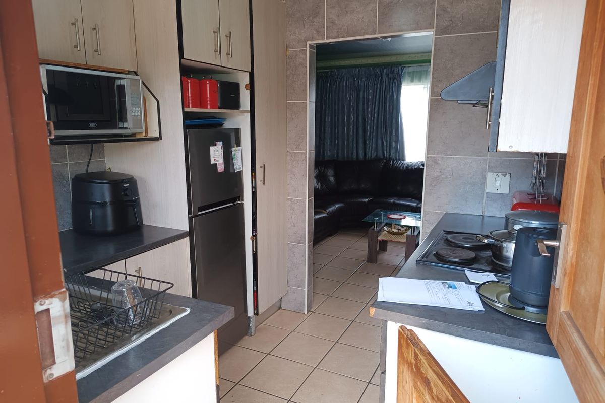 Functional kitchen featuring built-in cabinetry, laminate countertops, and ceramic tile finishes, providing a practical workspace with direct access to the adjacent living area.