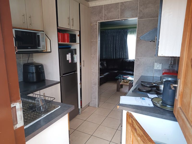 Functional kitchen featuring built-in cabinetry, laminate countertops, and ceramic tile finishes, providing a practical workspace with direct access to the adjacent living area.