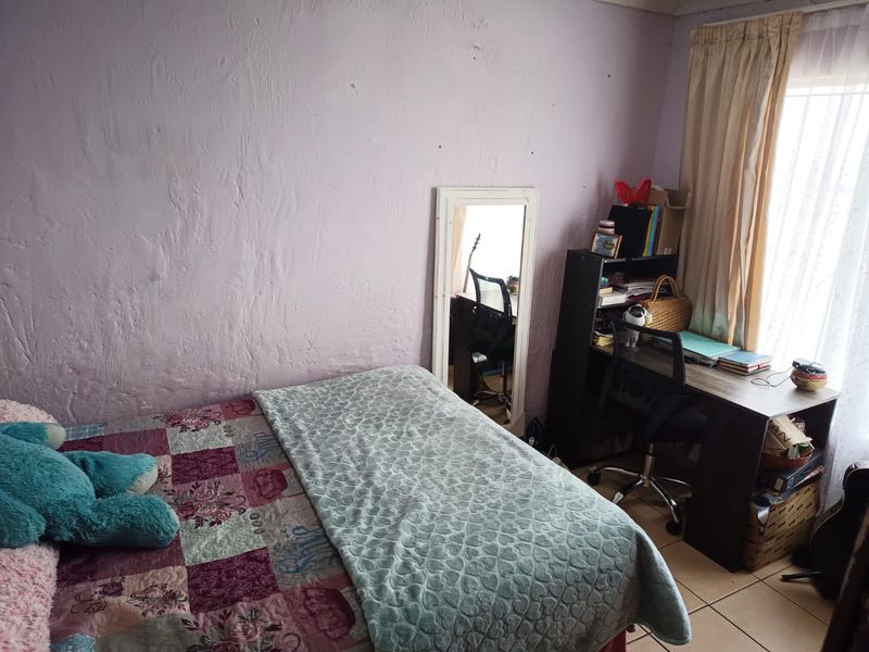 A bedroom featuring tiled flooring and textured walls, offering a functional space that could benefit from cosmetic updates and fresh paint.
