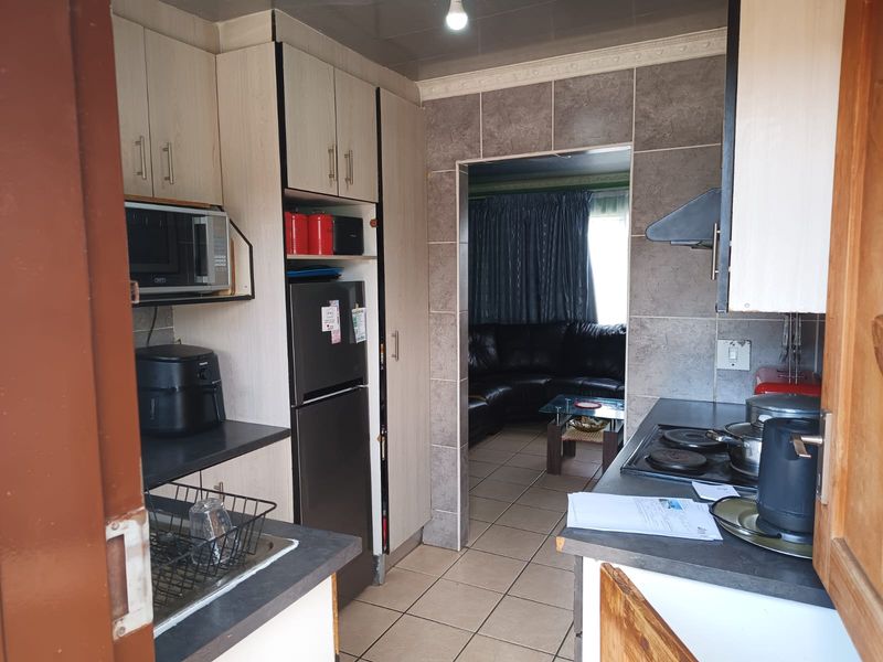 A functional kitchen featuring built-in cabinetry, laminate countertops, a built-in hob, and an extractor fan, with tiled flooring and wall finishes.