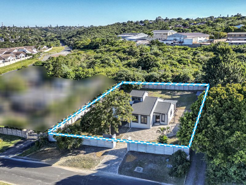 Aerial view of the property showing the house, paved driveway, and perimeter boundary walls within a suburban setting.