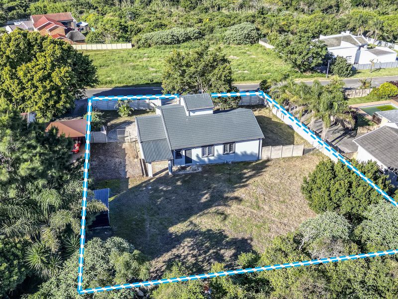 Aerial view of a residential property featuring a tiled roof house, paved driveway, carport, and a large garden area enclosed by perimeter fencing.
