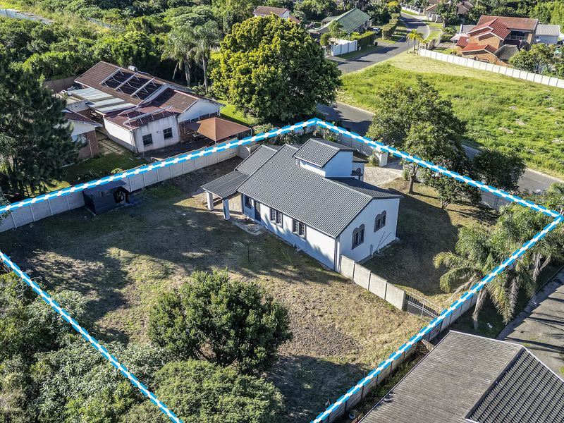 Aerial view of a residential property featuring a metal roof, expansive garden space, and secure perimeter walling within a suburban neighborhood.