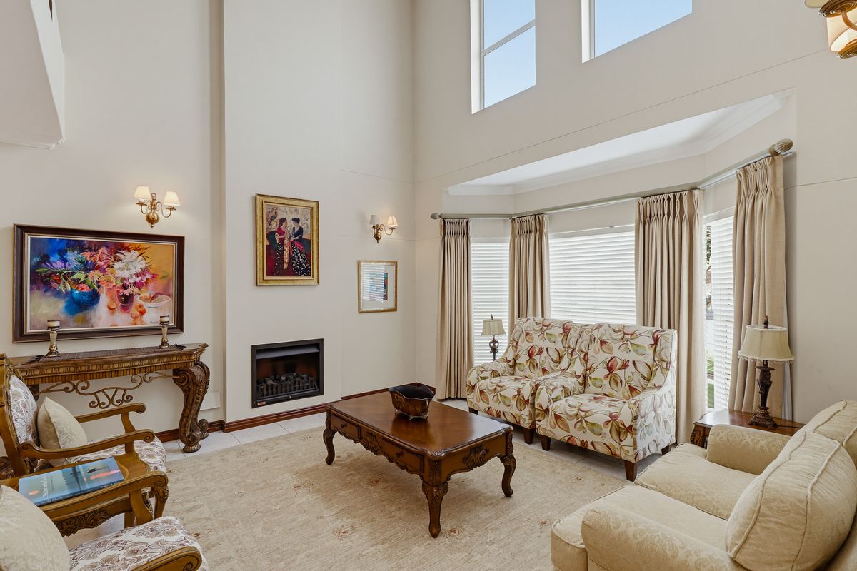 Spacious living room featuring a double-volume ceiling, built-in fireplace, and a large bay window that provides ample natural light.
