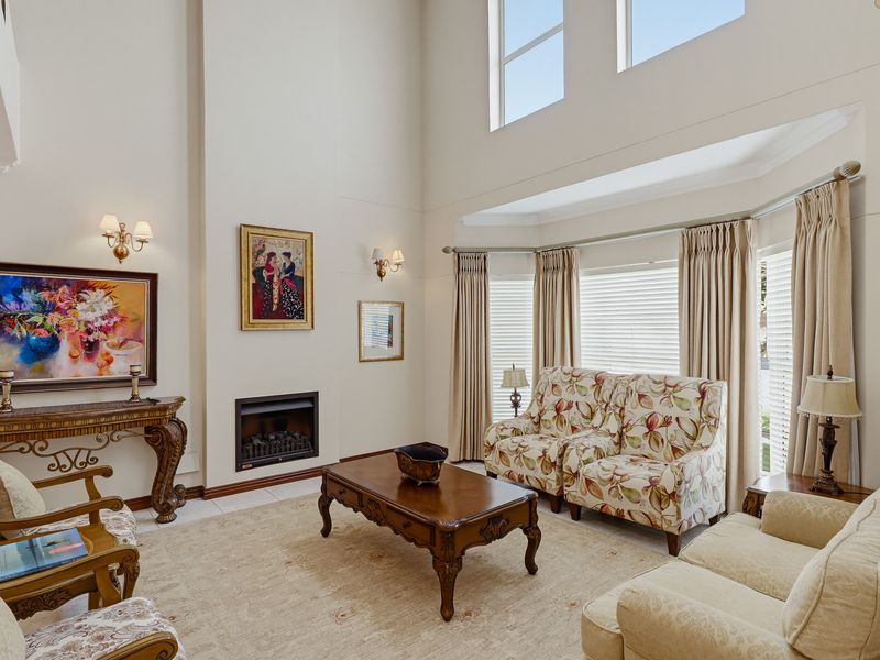 Spacious living room featuring a double-volume ceiling, built-in fireplace, and a large bay window that provides ample natural light.