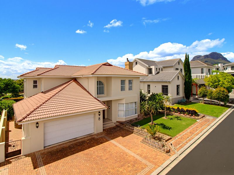 A well-maintained double-story residence featuring a tiled roof, brick-paved driveway, double garage, and landscaped front garden in a suburban setting.