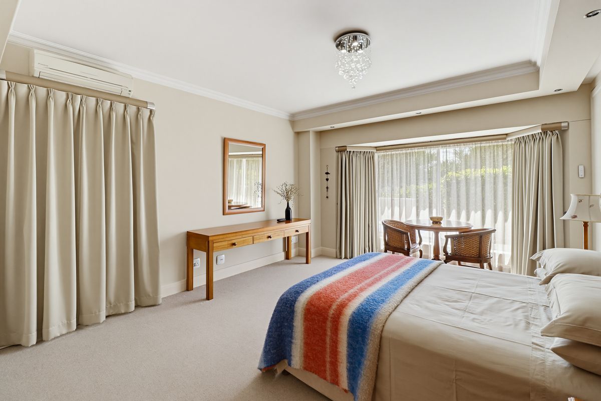 A well-maintained bedroom featuring neutral walls, carpeted flooring, crown molding, recessed lighting, and a bay window with integrated air conditioning.