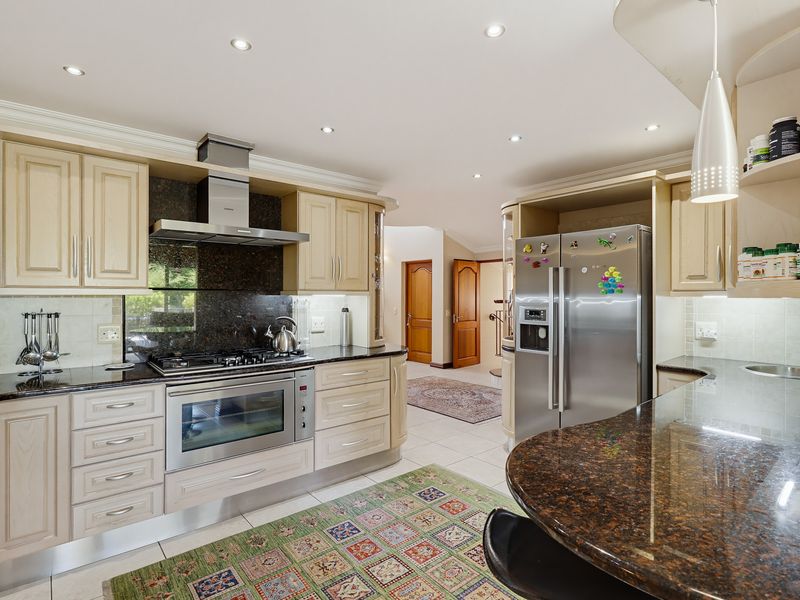 A well-appointed kitchen featuring granite countertops, built-in oven, gas hob, extractor fan, and ample cabinetry with a breakfast bar.