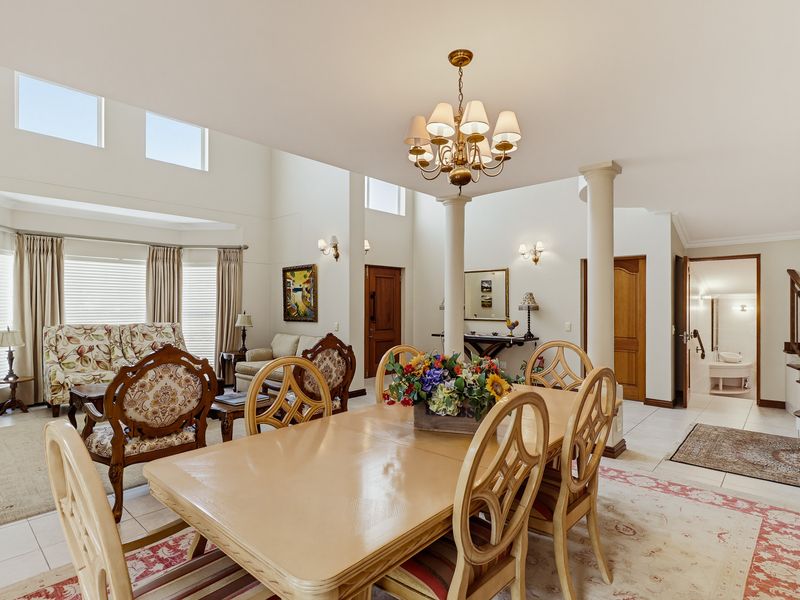 Spacious open-plan living and dining area featuring high vaulted ceilings, structural columns, tiled flooring, and abundant natural light from clerestory windows.