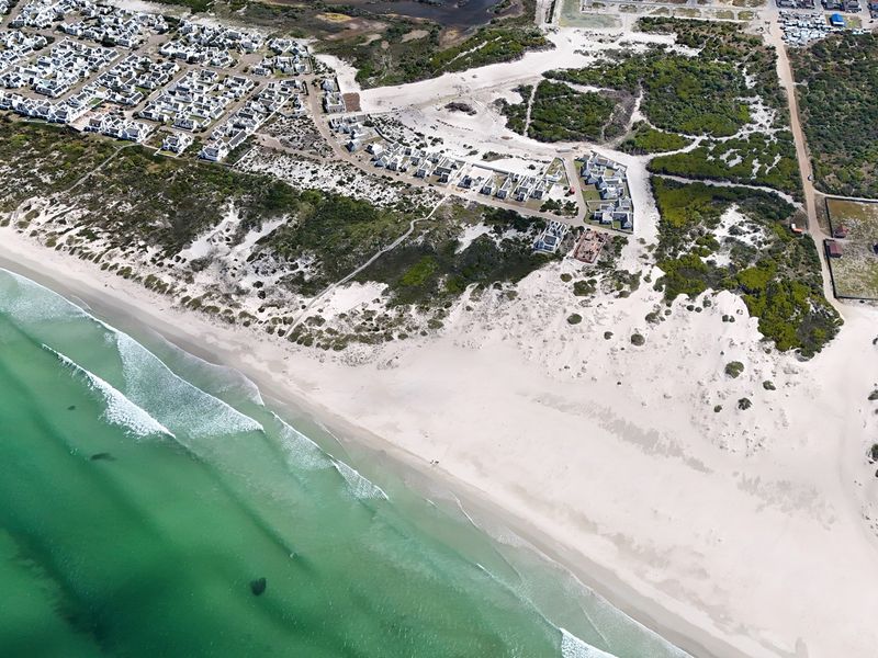 An aerial view of the coastal residential area, showcasing the proximity to the beach, dunes, and surrounding natural landscape.