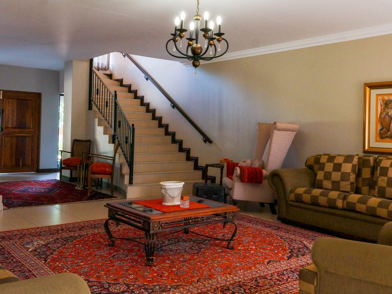 Spacious living area featuring a prominent staircase with a wrought iron balustrade, tiled flooring, and elegant cove cornicing.