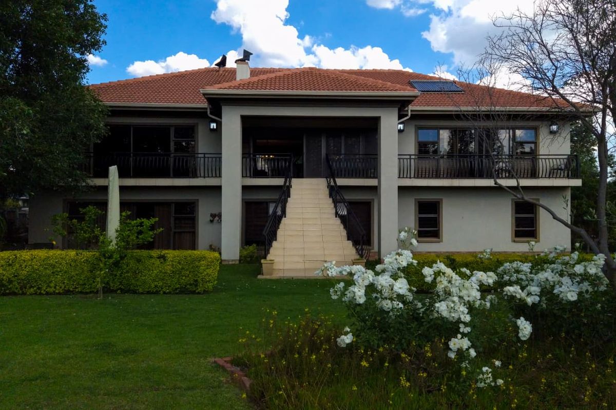 Rear view of a two-story residence featuring a terracotta tile roof, solar water heating, a spacious balcony, and a central external staircase leading to the garden.