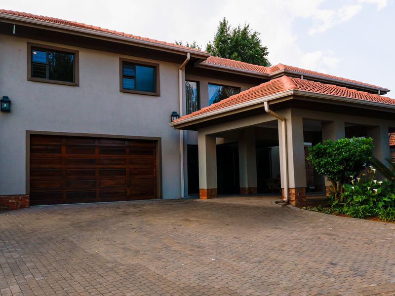 Front elevation of a double-story house featuring a paved driveway, integrated double garage, and a covered entrance with tiled roofing.