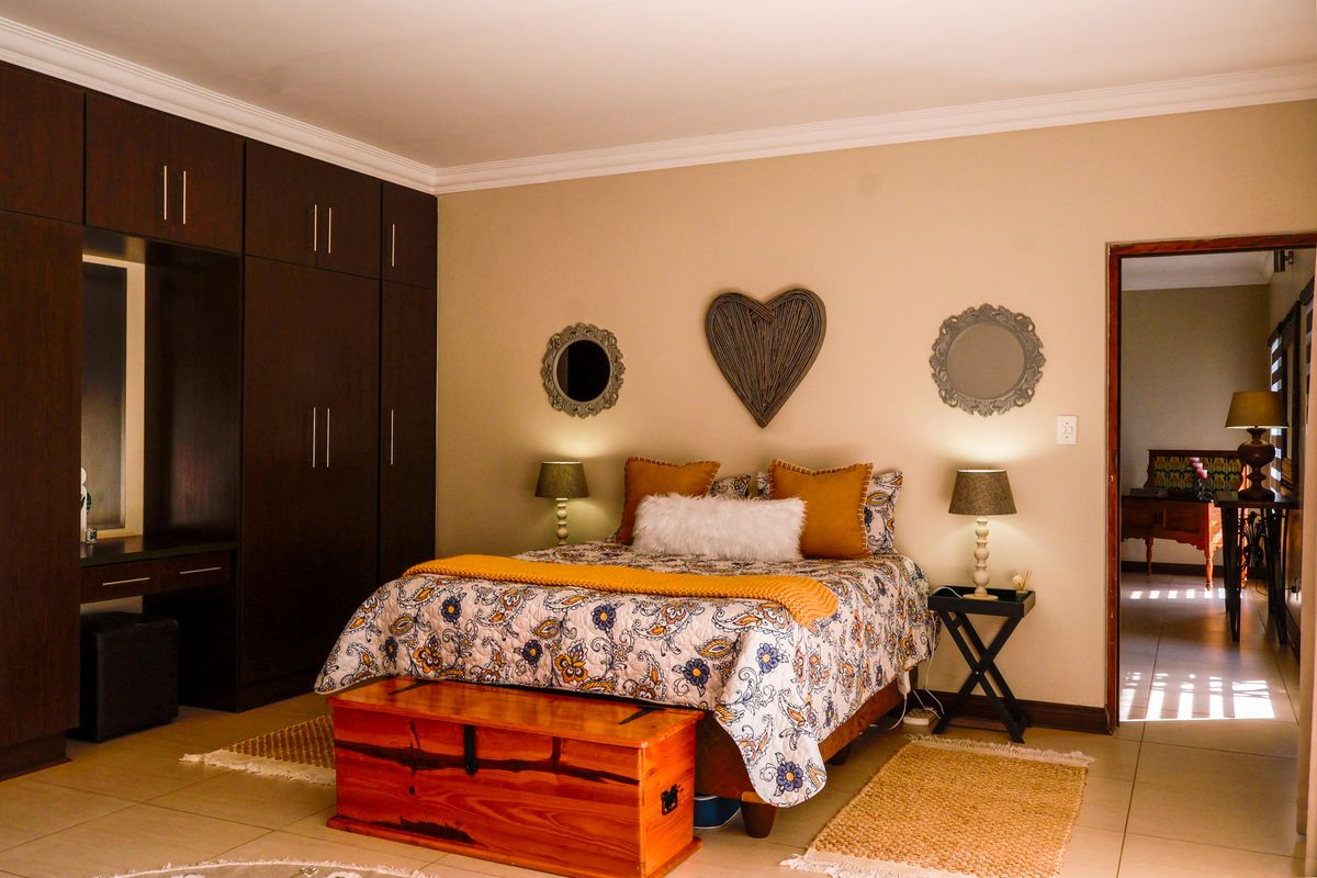 A well-maintained bedroom featuring extensive dark wood built-in cupboards, neutral wall tones, and tiled flooring.