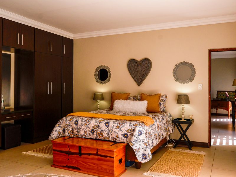 A well-maintained bedroom featuring extensive dark wood built-in cupboards, neutral wall tones, and tiled flooring.