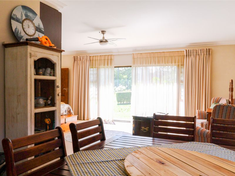 A living room area featuring a ceiling fan, coving, and large sliding glass doors that provide access to the garden.