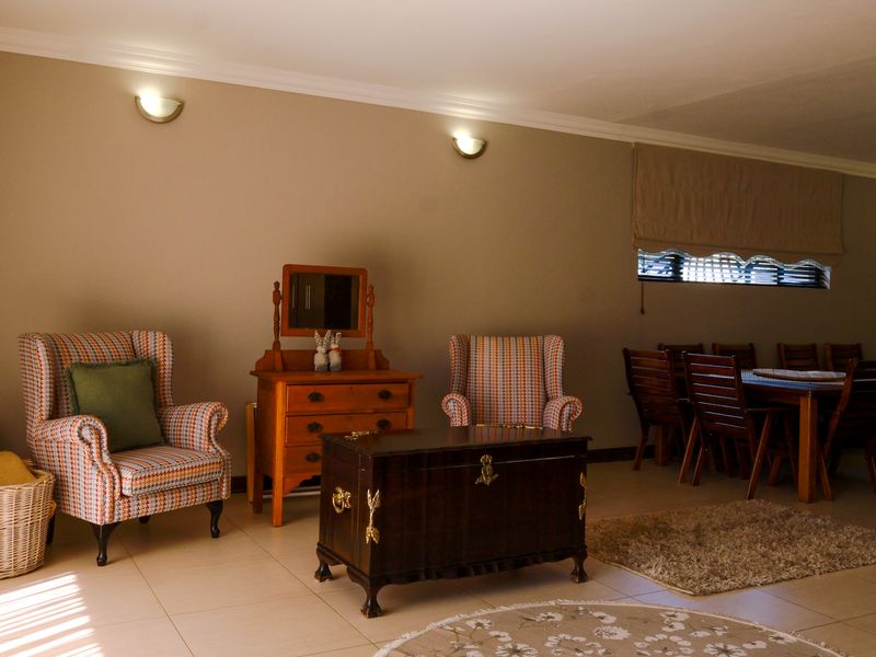A spacious living and dining area featuring neutral wall tones, tiled flooring, and wall-mounted lighting, offering a versatile layout for comfortable family living.