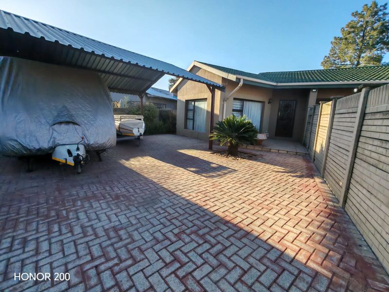 Front exterior view featuring a paved driveway, a covered carport structure, and a well-maintained house facade with tiled roofing.