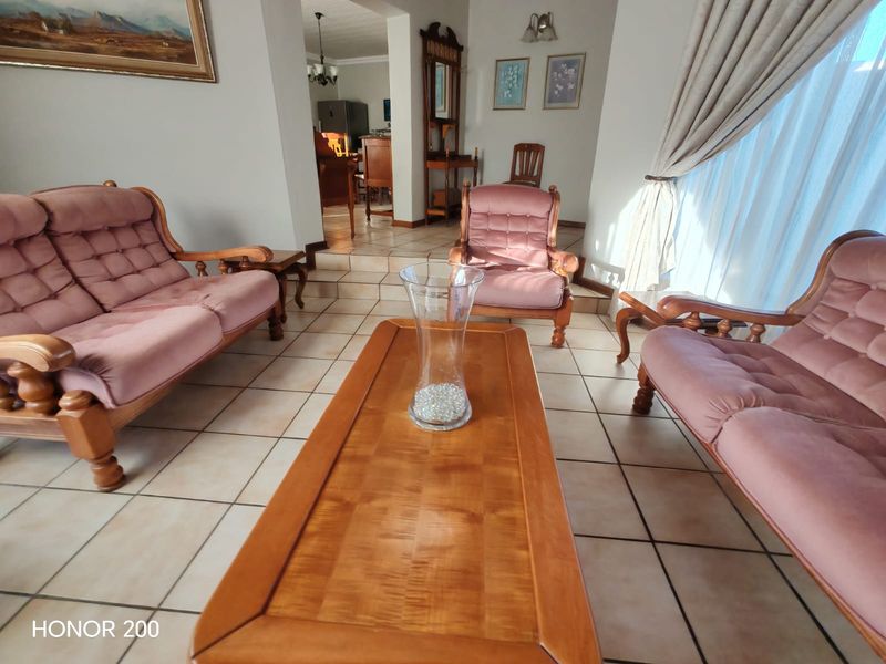 A spacious living area featuring tiled flooring and a stepped transition leading to an adjacent room, offering a functional and open layout.