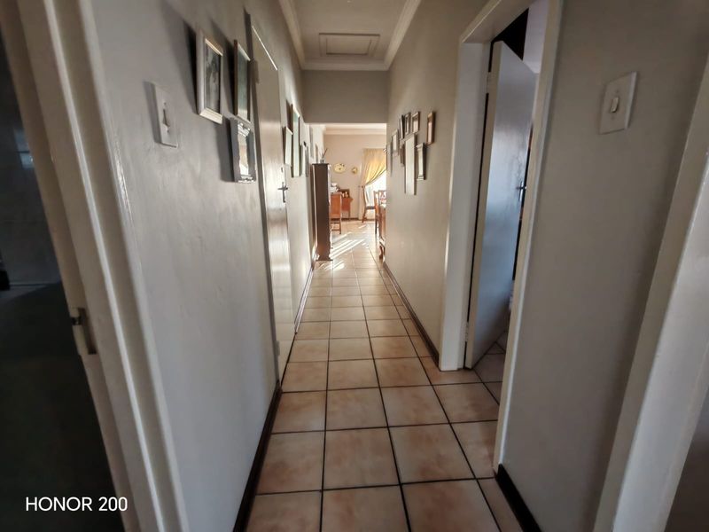 A functional hallway featuring tiled flooring and a ceiling access hatch, providing a clear transition between the home's living areas.