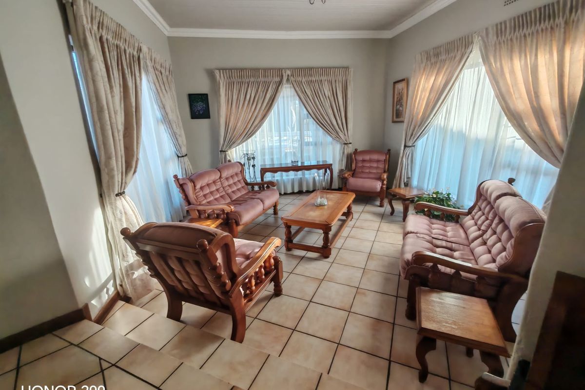 A spacious living room featuring tiled flooring, a tongue and groove ceiling, and large windows that provide ample natural light.