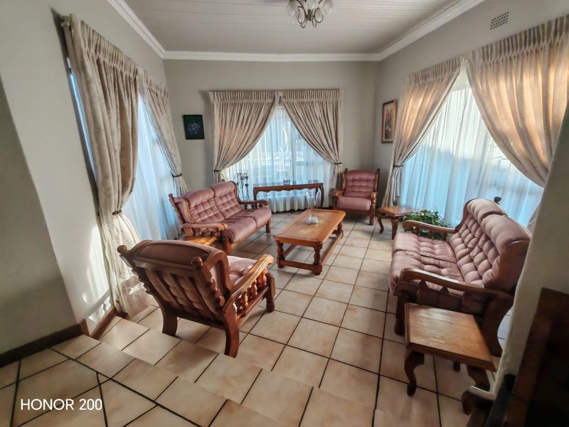 A spacious living room featuring tiled flooring, a tongue and groove ceiling, and large windows that provide ample natural light.