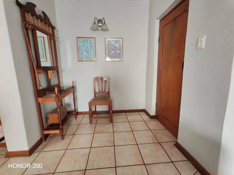 A functional entry hall featuring ceramic floor tiles, a solid wooden door, and neutral wall finishes.