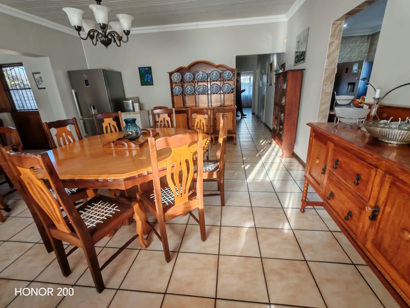 A spacious dining room featuring tiled flooring, a classic chandelier, and coved ceiling details, providing a functional area for family meals.