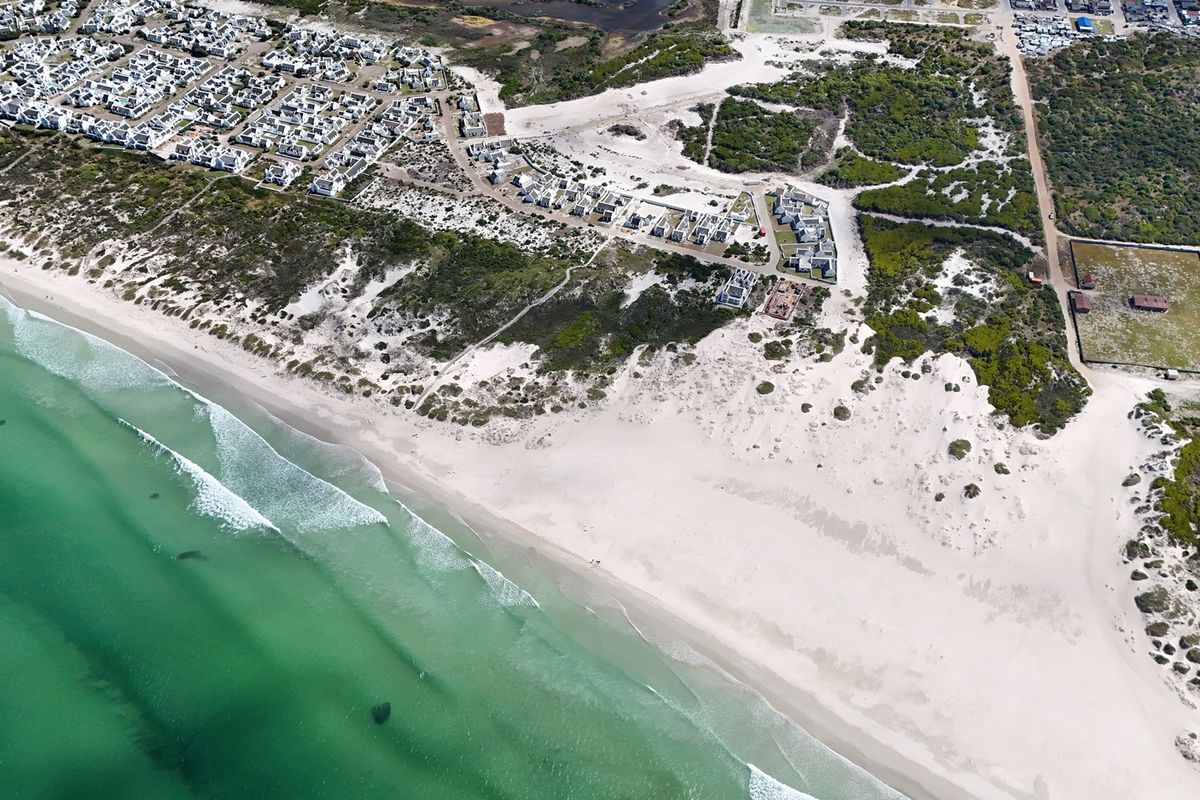 An aerial view of the coastal residential area, showcasing the proximity to the beach, dunes, and surrounding natural landscape.