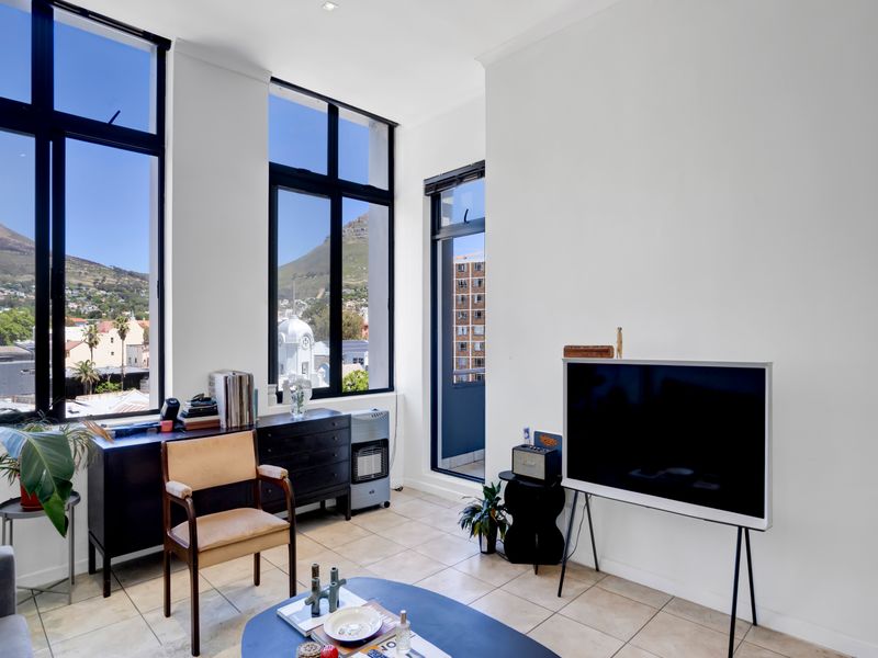 Bright living room featuring expansive floor-to-ceiling windows with mountain views, tiled flooring, and direct access to a private balcony.