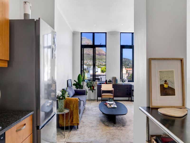 Bright open-plan living area featuring large windows with mountain views, seamlessly connected to a modern kitchen with stone countertops and ample cabinetry.
