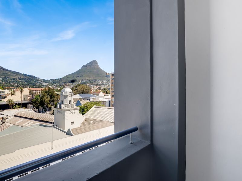 A clear view of the city and mountain landscape captured from a balcony with a metal railing.