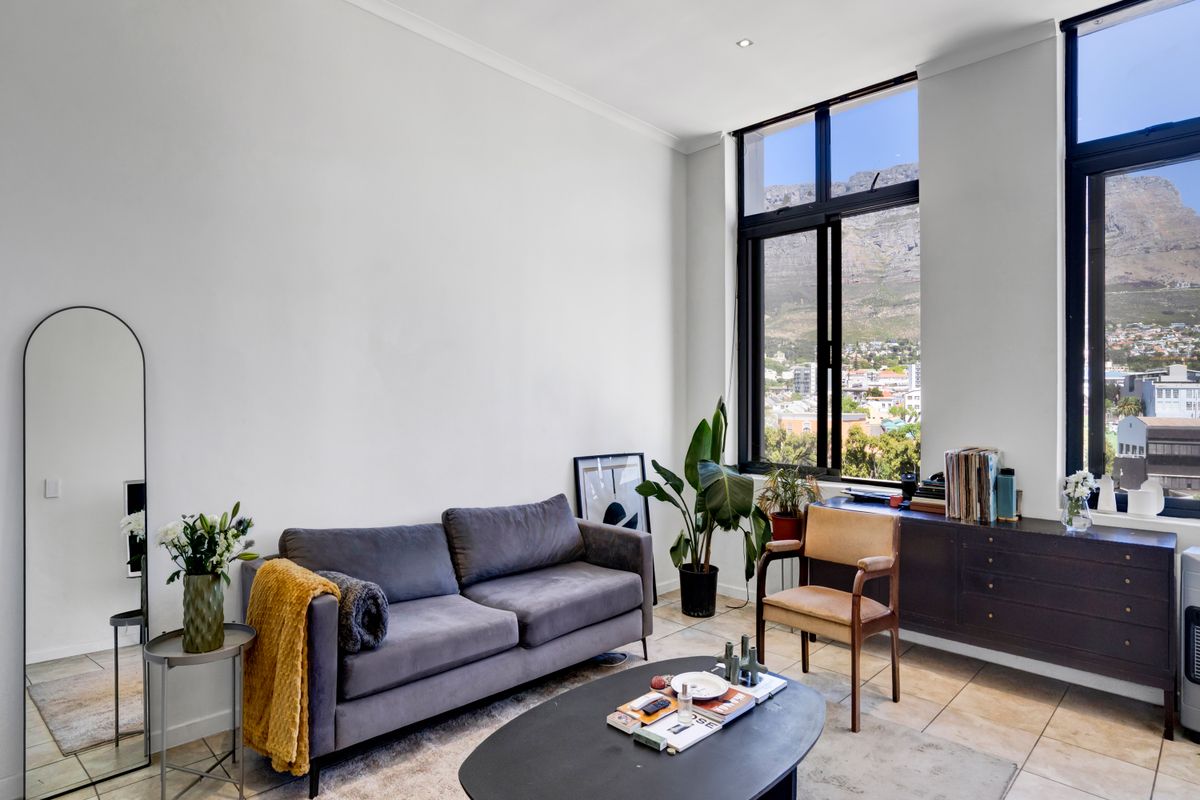 Bright living room featuring large windows with mountain views, neutral tiled flooring, and clean white walls.
