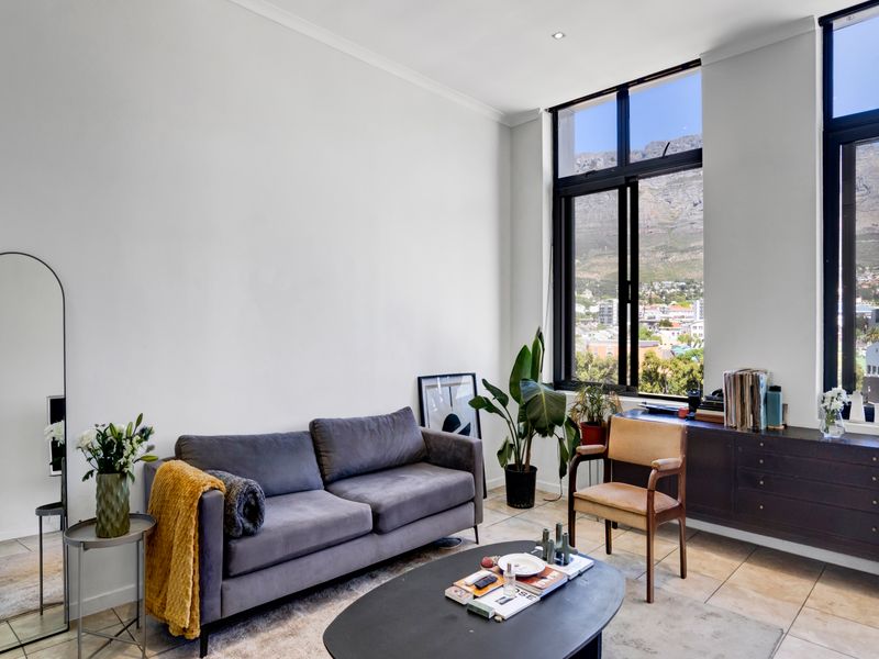Bright living room featuring large windows with mountain views, neutral tiled flooring, and clean white walls.