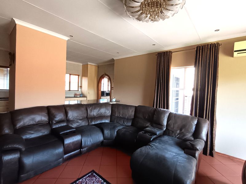 Spacious open-plan living area featuring tiled flooring, recessed lighting, and an integrated air conditioning unit, with a view through to the kitchen area.