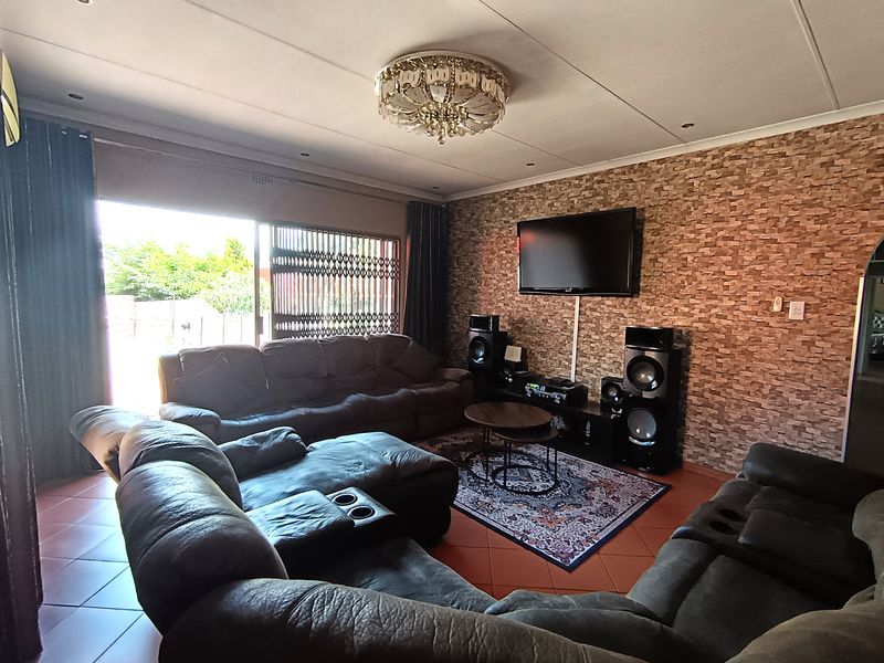 Spacious living room featuring a textured stone veneer accent wall, tiled flooring, and large sliding doors providing access to the outdoor area.